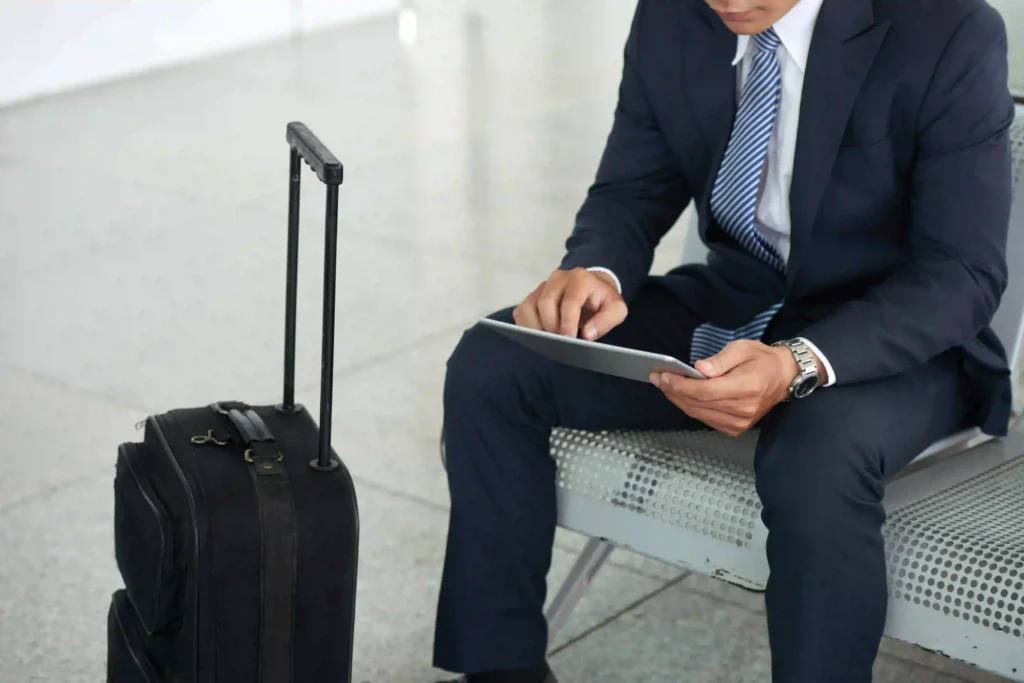 Businessman sitting on a chair with a trolley in front of him and a tablet in his hand