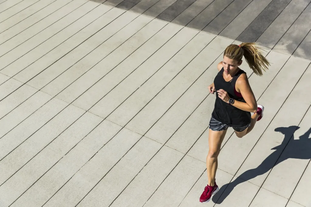 Sporty dressed woman running on a road