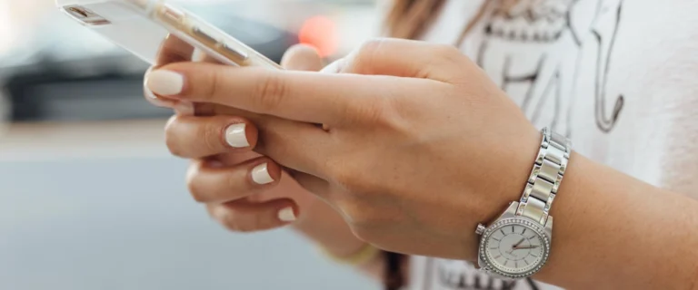 Nell'immagine si vedono le mani di una ragazza che digitano sulla tastiera di uno smartphone